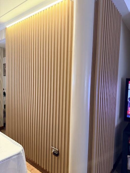 Pared revestida con wallpanel símil madera clara y luz LED